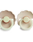Two Frigg Daisy Night Rubber Cream and Croissant pacifiers on a white background