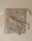 Two mushie Water Resistant Wet Bags with zippers and ribbon loops, featuring a floral design in orange and green, are placed on a neutral surface—ideal for diaper bag storage.