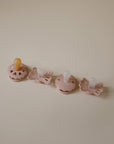 Set of four Blush baby pacifiers on a beige background.