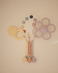 The mushie Silicone Pacifier Clip | Hera features pastel, food-grade silicone teethers in shapes like a flower, palette, and sun hanging from three beaded pacifier clips, all with a soft minimalist design on a neutral background.