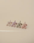 Four small mushie Figurine Teether pastel balloon dogs on a plain, light background.