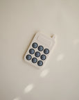 The mushie Phone Press Toy is a minimalist, toy-like retro mobile phone with a light beige body and nine large dark buttons, designed for sensory exploration.