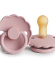 The FRIGG Daisy Natural Rubber Pacifier 2-Pack in Baby Pink features two pacifiers—one upright, one flat—to show front and side views, both with scalloped edges and yellowish natural rubber nipples. Limited Edition.