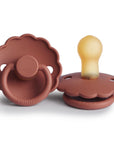 Two FRIGG Daisy Natural Rubber Pacifiers in Baked Clay; one lies flat revealing the latex nipple, while the other stands upright highlighting the handle and embossed FRIGG logo. Limited Edition 2-Pack.