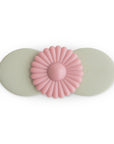 The mushie Suction Spinner Toy in Blossom features two overlapping ovals and a pink daisy design, made from food-grade silicone. "mushie" is embossed on the right oval, providing a gentle sensory experience.
