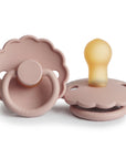 Two FRIGG Daisy Natural Rubber Pacifiers in blush, featuring scalloped edges and round handles—one upright showing the latex nipple, the other flat to display the stylish handle. Limited Edition 2-Pack.