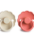 The FRIGG Daisy Natural Rubber Pacifier 2-Pack features one cream and one coral pink scalloped pacifier with natural rubber nipples, round handles, and the FRIGG logo embossed on each, shown side by side on a white background.