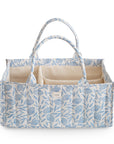 The mushie Diaper Caddy in Blue Flowers features a rectangular quilted design, beige interior, multiple compartments, and two handles, shown against a white background.