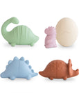 The mushie Dino Mold Free Bath Play Set features four colorful dinosaur-shaped silicone bath toys in green, purple, blue, and brown plus a cream cracked egg toy, all arranged on a white background.