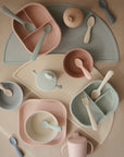 Discover mushie Silicone Toddler Starter Spoons in soft pink, green, and blue—perfect for encouraging independent feeding with pastel-colored children’s tableware.
