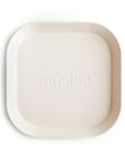 The mushie Square Dinnerware Plate is an off-white, BPA-free plastic baby plate with a minimalist design, rounded corners, raised edges, and "mushie" embossed in the center.