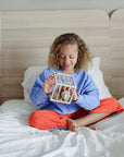 Smiling child plays with mushie's Elastic Shape Sorter, building fine motor skills.
