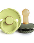 The Mushie FRIGG Rope Natural Rubber Pacifier 2-Pack features two green pacifiers with round, textured edges and ring handles—one upright to display the nipple, one flat—essential baby items in calming hues.
