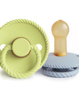 The Mushie FRIGG Rope Natural Rubber Pacifier 2-Pack features two modern baby essentials: one with a yellow-green rope-like edge and ring handle, the other in light blue showing its natural rubber latex nipple.