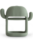 The mushie No-Drop Cactus Teether (Dried Thyme) is a silicone cup holder shaped like a cactus with two arms and a ribbed dome top. Its open center fits a cup, combining playful baby teether style with practical, modern design.