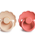 The FRIGG Daisy Natural Rubber Pacifier 2-Pack features two daisy-shaped pacifiers—one light beige, one muted pink—with scalloped edges, circular handles, and “FRIGG” embossed on each.