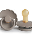 Two FRIGG Daisy Natural Rubber Pacifiers in Portobello, one lying flat to display the natural rubber nipple, the other upright showing the front and handle. Both have scalloped edges and FRIGG embossed on the base. Limited Edition 2-Pack.