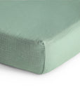Close-up of the mushie Extra Soft Muslin Crib Sheet in light green, showing the soft cotton texture and neat stitching—an ideal, breathable bedding choice for your baby's crib.