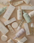 Mushie Baby Oil bottles and boxes with natural ingredients on a beige surface.