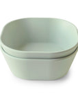 Two sage green mushie Square Dinnerware Bowls with rounded corners and a matte finish are stacked together. The BPA-free plastic set is displayed against a white background.