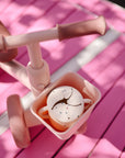 Pink toddler tricycle with a mushie Snack Cup, spill-proof and silicone, in the basket.