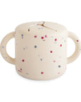 Mushie Snack Cup: cream silicone, two handles, pink & blue star patterns.