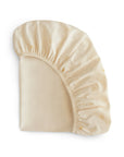 The mushie Stretchy MINI Crib Sheet is a breathable, cream-colored sheet made from organic cotton with a gathered elastic edge and cute yellow sun patterns on a white background.