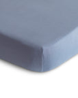 Close-up of the corner of a mushie Stretchy MINI Crib Sheet in light blue, made from breathable organic cotton with a smooth finish and neat lines, shown against a white background.
