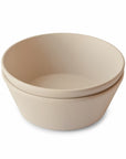 Two nested mushie Round Dinnerware Bowls made of BPA-free plastic in beige are stacked together on a plain white background.