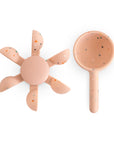 Mushie Water Wheel Bath Toy: Peach silicone flower & scoop with speckles on white background.