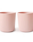 Two round, light pink mushie Dinnerware Cups made from non-toxic materials are placed side by side on a white background.