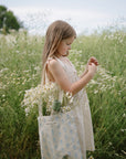 Young girl explores a field holding wildflowers and mushie Kaleidoscopes.