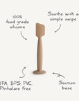 The Mushie Diaper Cream Applicator, shown in tan silicone with a suction base, features 100% food-grade silicone. Highlights include “Soothe with a simple swipe,” and it's BPA, BPS, PVC & Phthalate free.