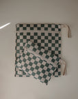 Two rectangular mushie Water Resistant Wet Bags with green and white check patterns and white zippers—one large, one small—each has a beige strap. They're perfect for organizing essentials or diaper bag storage.
