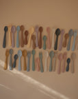 The mushie Silicone Toddler Starter Spoons feature colorful, pastel tones and are arranged neatly in rows—perfectly designed to encourage independent feeding for babies and toddlers.