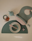 Mushie Teething Ring set: food-grade silicone ring, bowl, cup, spoon, bib, and mat.