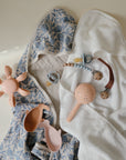 Baby items: floral hooded towel, pacifiers w/clips, and mushie Water Wheel Bath Toy in fun colors.