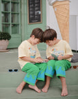 Two young boys play outside with a mushie Silicone Sensory Toy while sitting on steps.