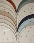 The mushie Silicone Placemat is made from food-grade silicone in muted colors, featuring playful patterns and neatly arranged in overlapping rows.