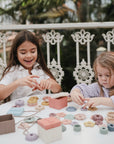 Two young girls build fine motor skills with the mushie Bead Lacing Toy Set.