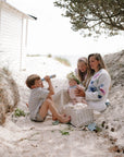 A family picnics on sand as kids play with mushie Kaleidoscopes.
