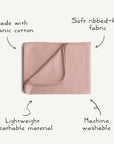 The Mushie Ribbed Baby Blanket is shown folded in pink, with text highlighting its soft, ribbed-knit organic cotton, lightweight and breathable design, and that it’s machine washable.