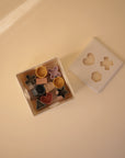 The mushie Shape Sorting Box features a square design with a removable white lid and colorful geometric blocks, each fitting into matching cutouts, to encourage hands-on learning and fine motor skills.