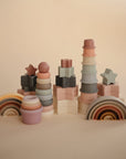 Mushie Stacking Cups Toy in assorted pastel colors is arranged on a neutral background. The smooth, matte finish and muted hygge tones are inspired by Rundetårn, adding cozy Danish charm to your baby's playtime.