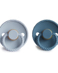 Two Frigg Moon Rubber pacifiers in Powder Blue and Ocean View with rope design on a shield on a white background