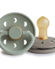 A product image of Frigg Moon Rubber pacifiers, one Sage and one Portobello, on a white background