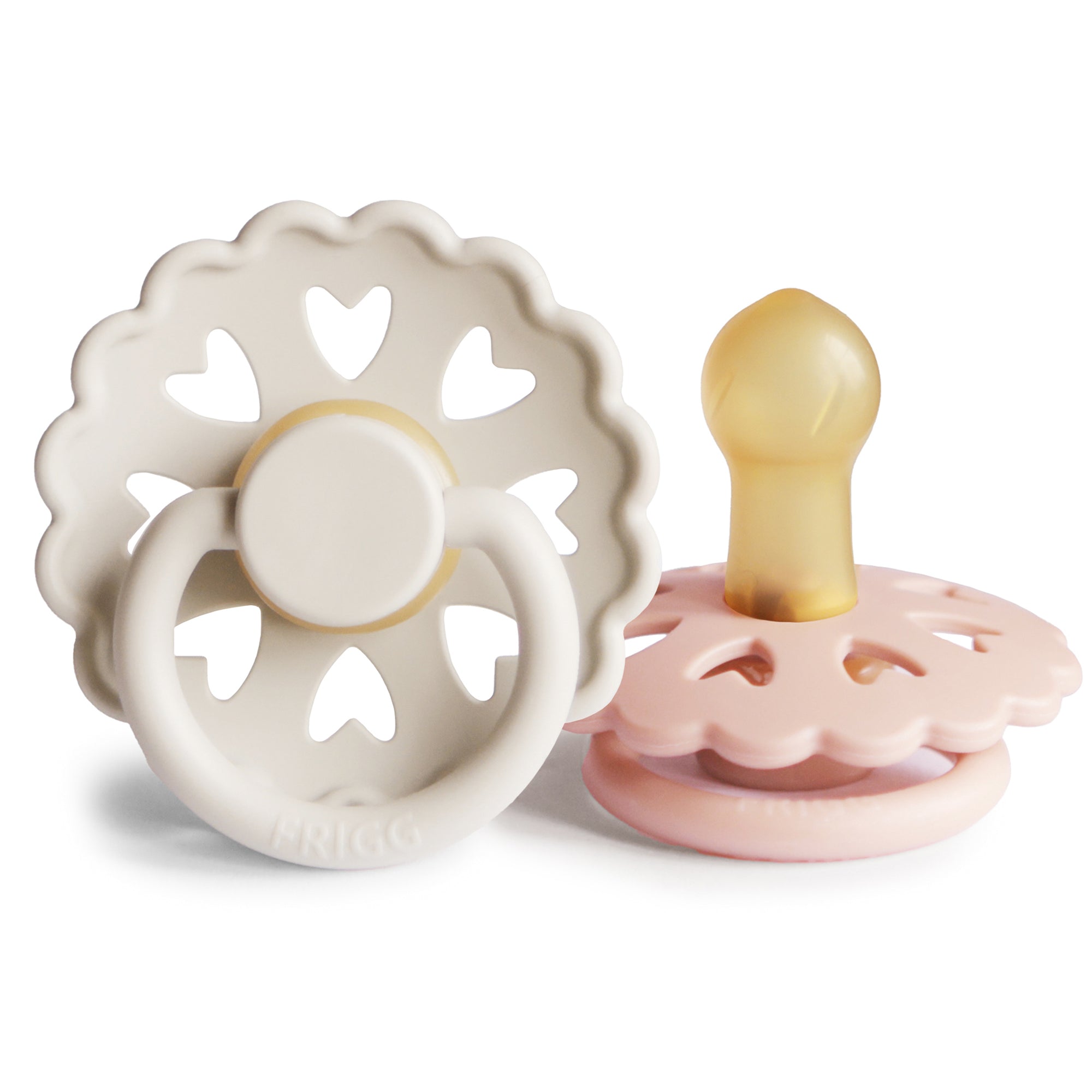 Product image of two Frigg Andersen Rubber baby pacifier, one Cream with heart designs and the other Blush, on a white background.