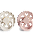 Two Frigg Andersen Rubber pacifiers, one Cream and one Blush, on a white background