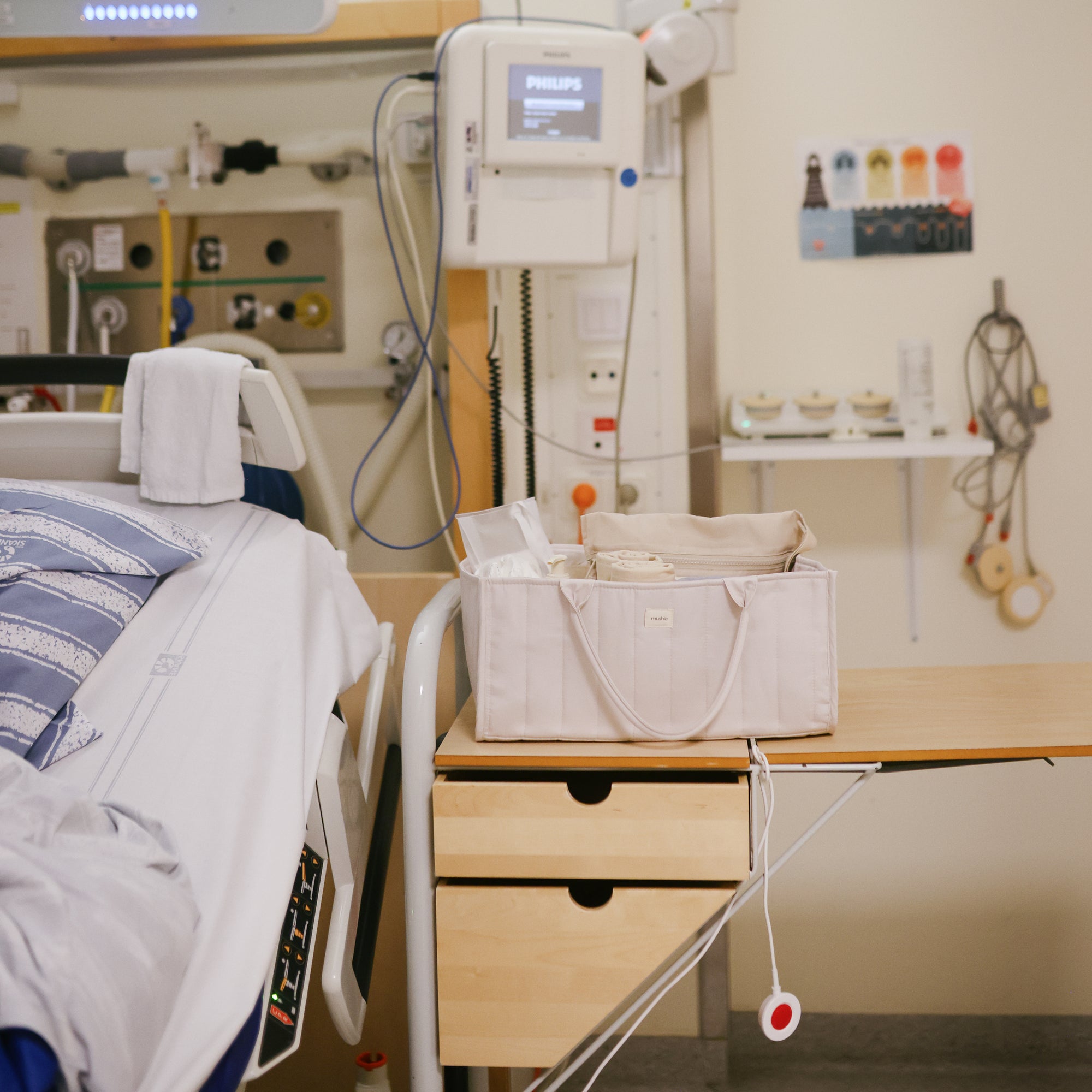 Lifestyle image in a hospital room with medical equipment and a Fog Diaper Caddy on the side table.