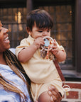 A woman holds a baby chewing on a textured, food-grade silicone mushie Teething Ring.